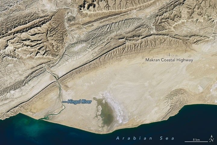 Satellite view of the Hingol River delta meeting the Arabian Sea, with the Makran Coastal Highway crossing the badlands